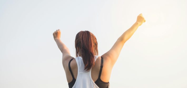 back of woman with arms in the air celebrating.